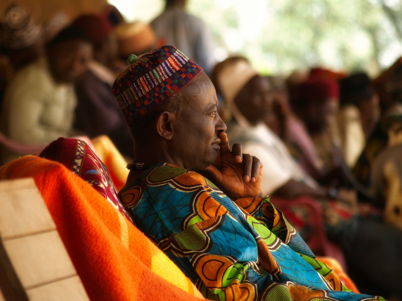 An elder in a colourful wrap listening