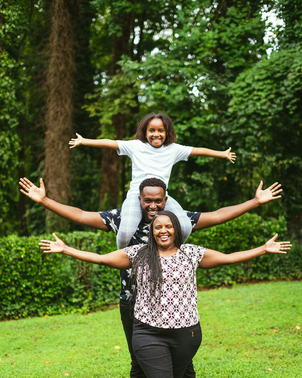 A family standing together on a lawn, the child lifted on the father's shoulders